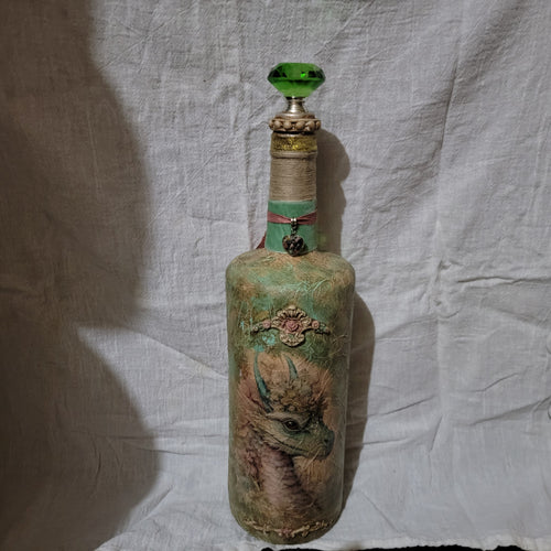 Hand-decorated decoupage bottle with vintage goat portrait, twine-wrapped neck, pink ribbon charm, gold glitter accents, and green glass jewel stopper